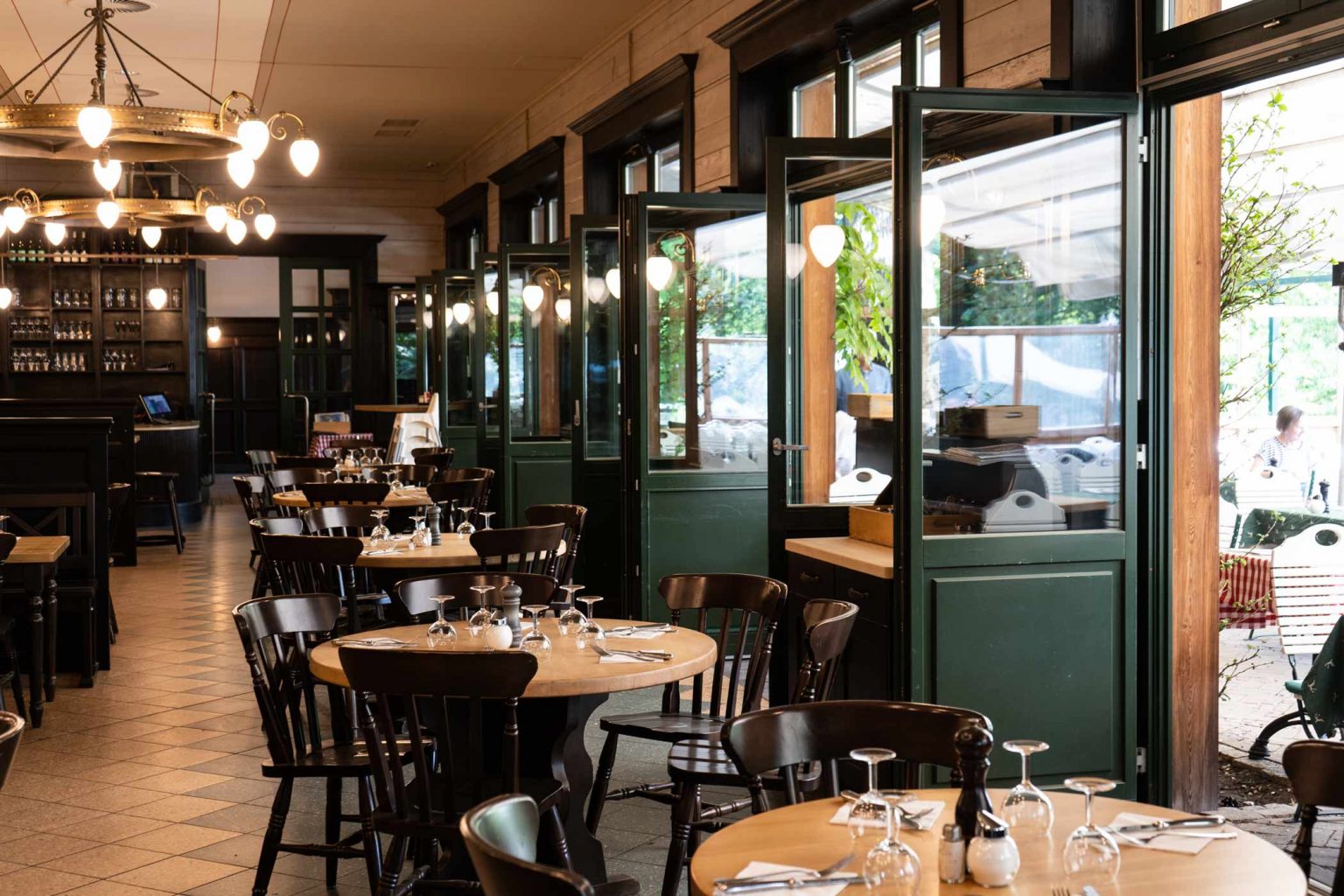 Gemütlicher Restaurantbereich mit gedeckten Tischen, Bar und Blick auf die Terrasse.