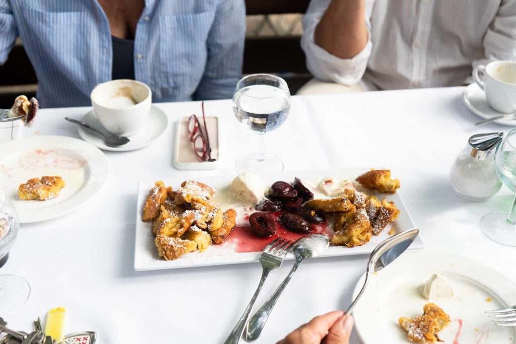 Dessertplatte mit Gebäck, Beeren und Kaffee auf weiß gedecktem Tisch im Restaurant.