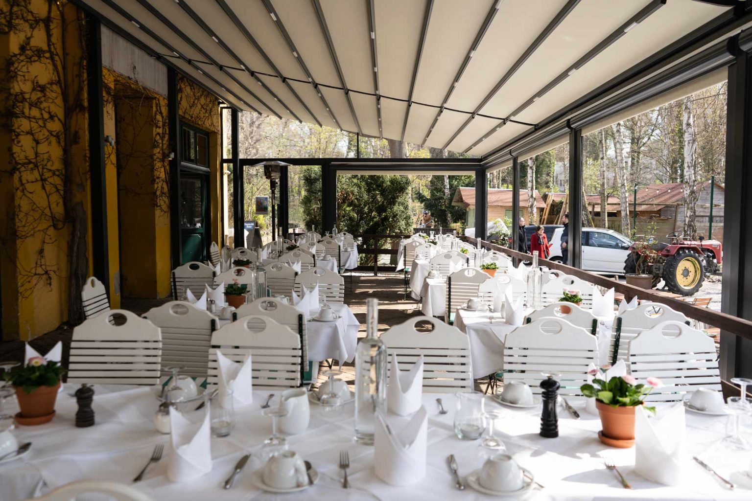 Lange gedeckte Tafel im hellen Restaurantbereich für Veranstaltungen und private Feiern.