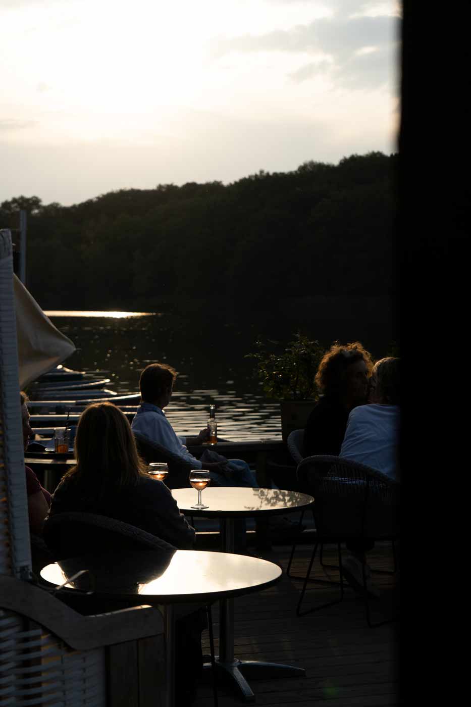 Gemütlicher Sitzplatz am Bootsverleih mit Blick auf den See bei Abendstimmung.