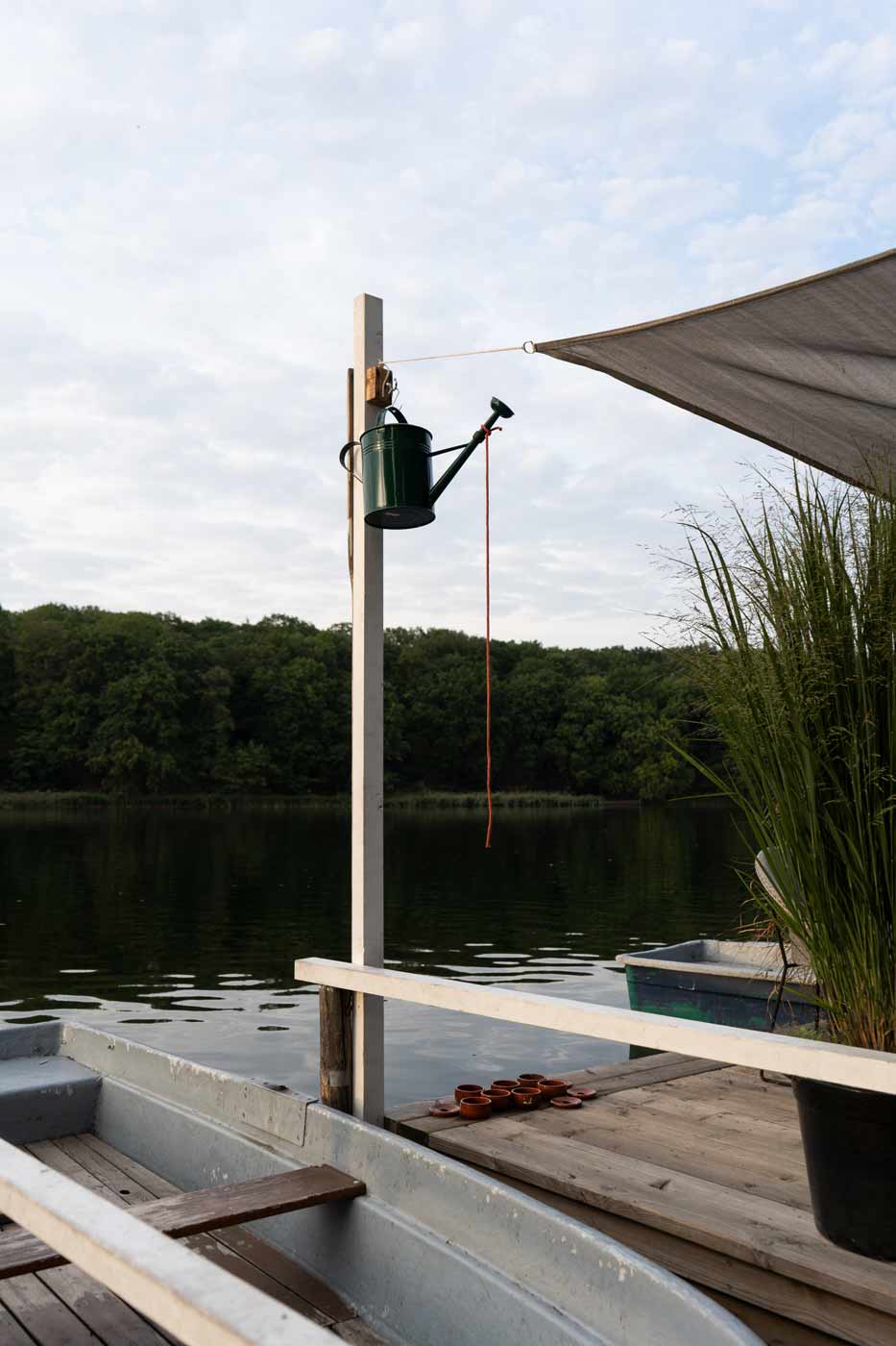 Bootssteg am See mit Ruderbooten und Blick auf die grüne Umgebung.