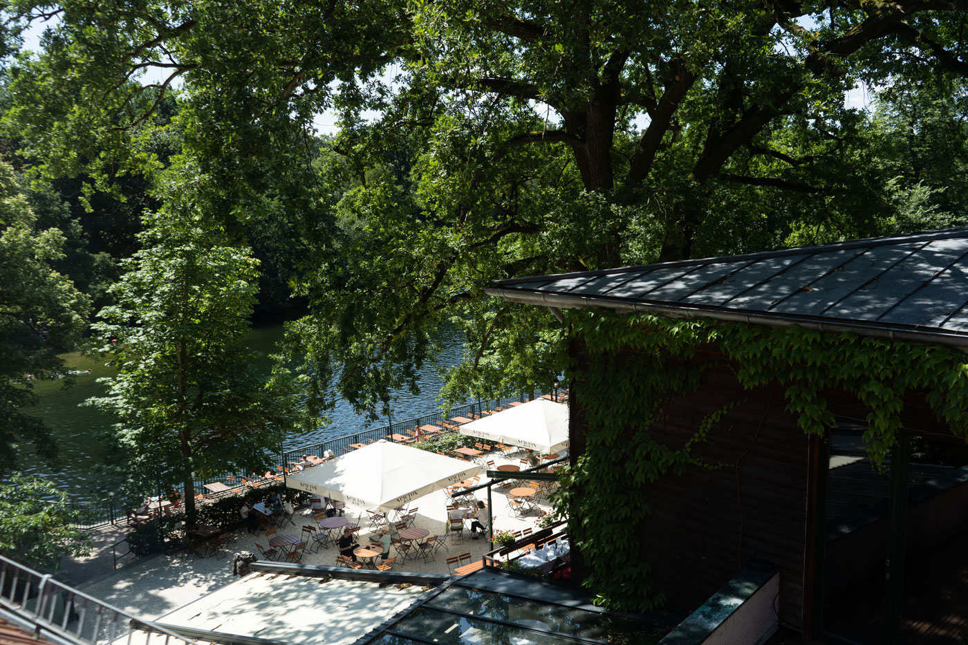 Schattiger Biergarten am See mit Terrasse, Sitzplätzen und Blick ins Grüne.