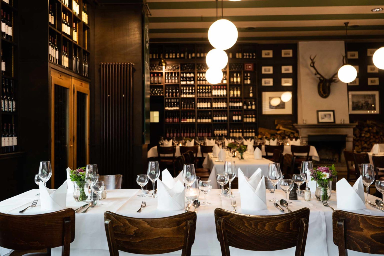 Restaurant in der Weinhandlung mit gedeckten Tischen, Weinregalen und warmem Licht.