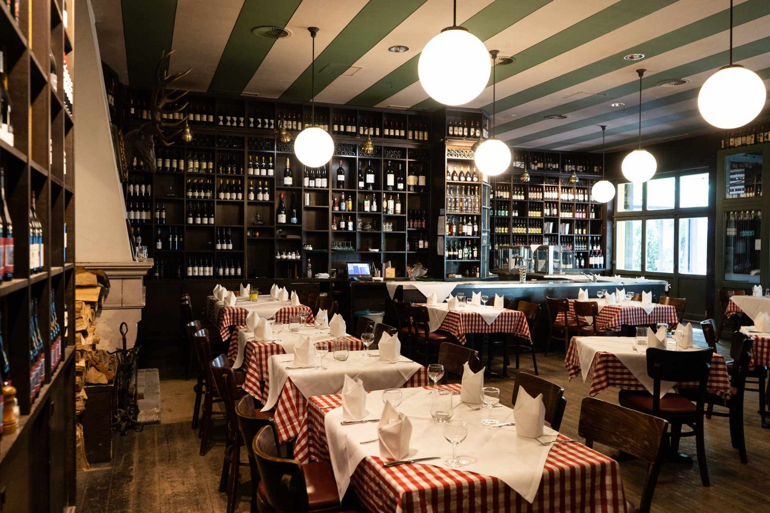 Restaurantbereich der Lutter & Wegner Weinhandlung mit gedeckten Tischen und Weinregalen.