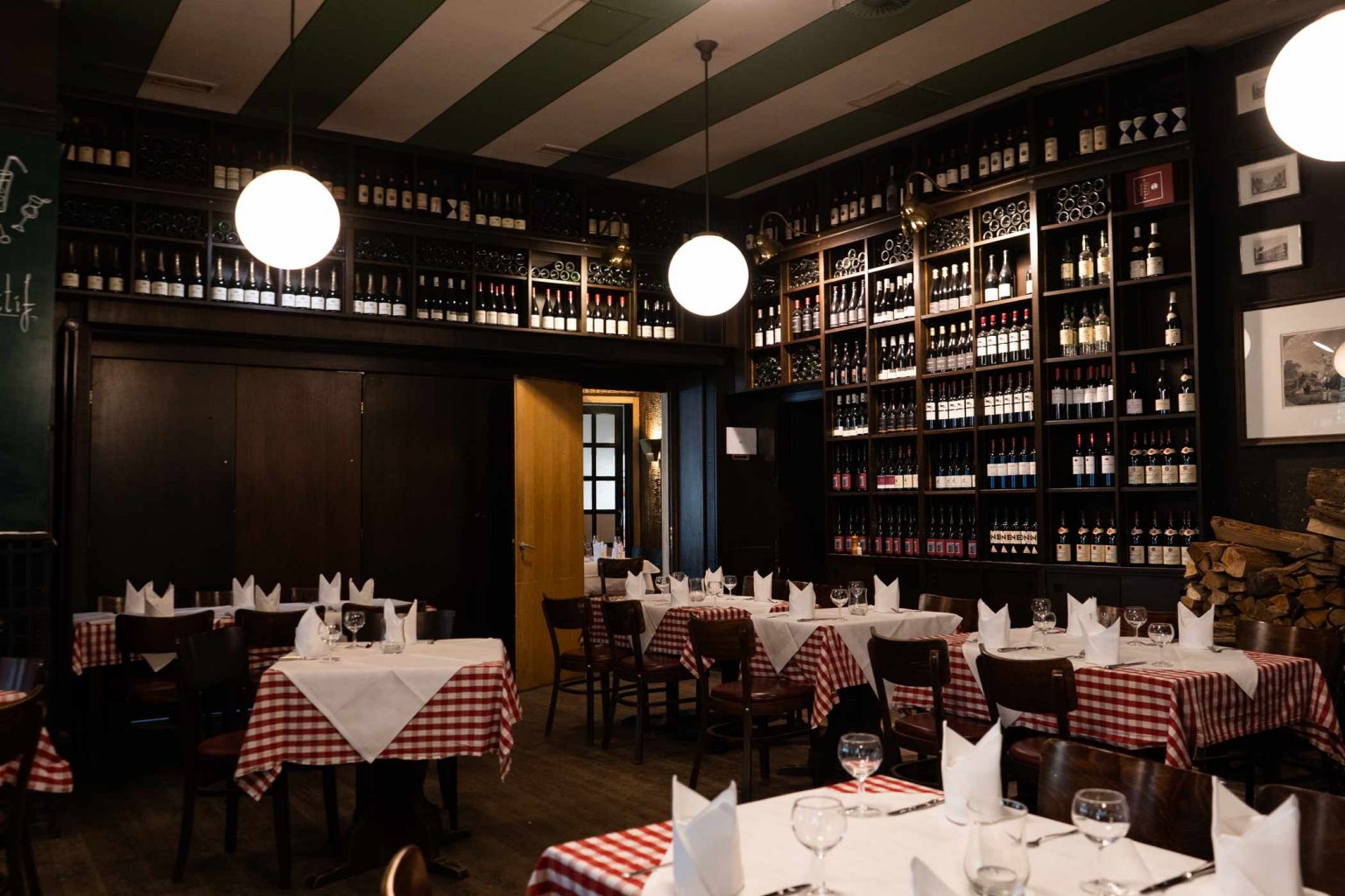Restaurantbereich mit Weinregalen, gedeckten Tischen und stilvollem Ambiente für Feiern.