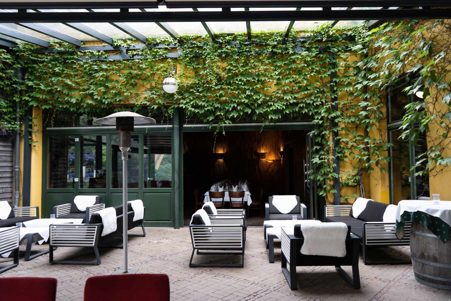 Grüne Terrasse mit Loungemöbeln und Pergola als gemütlicher Außenbereich für Events.