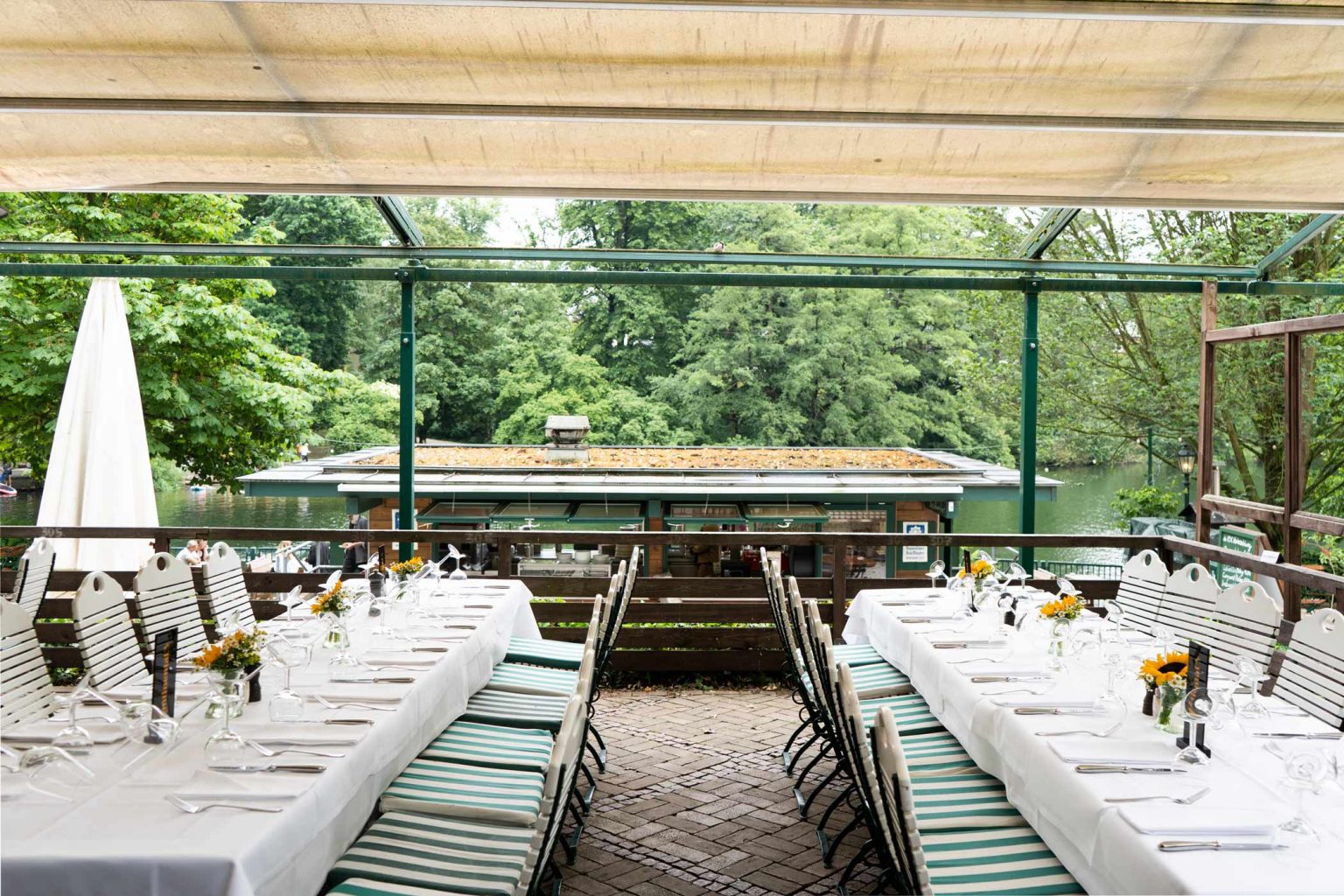 Überdachte Terrasse mit weißen Tischdecken, Markise und gemütlichem Außenbereich.