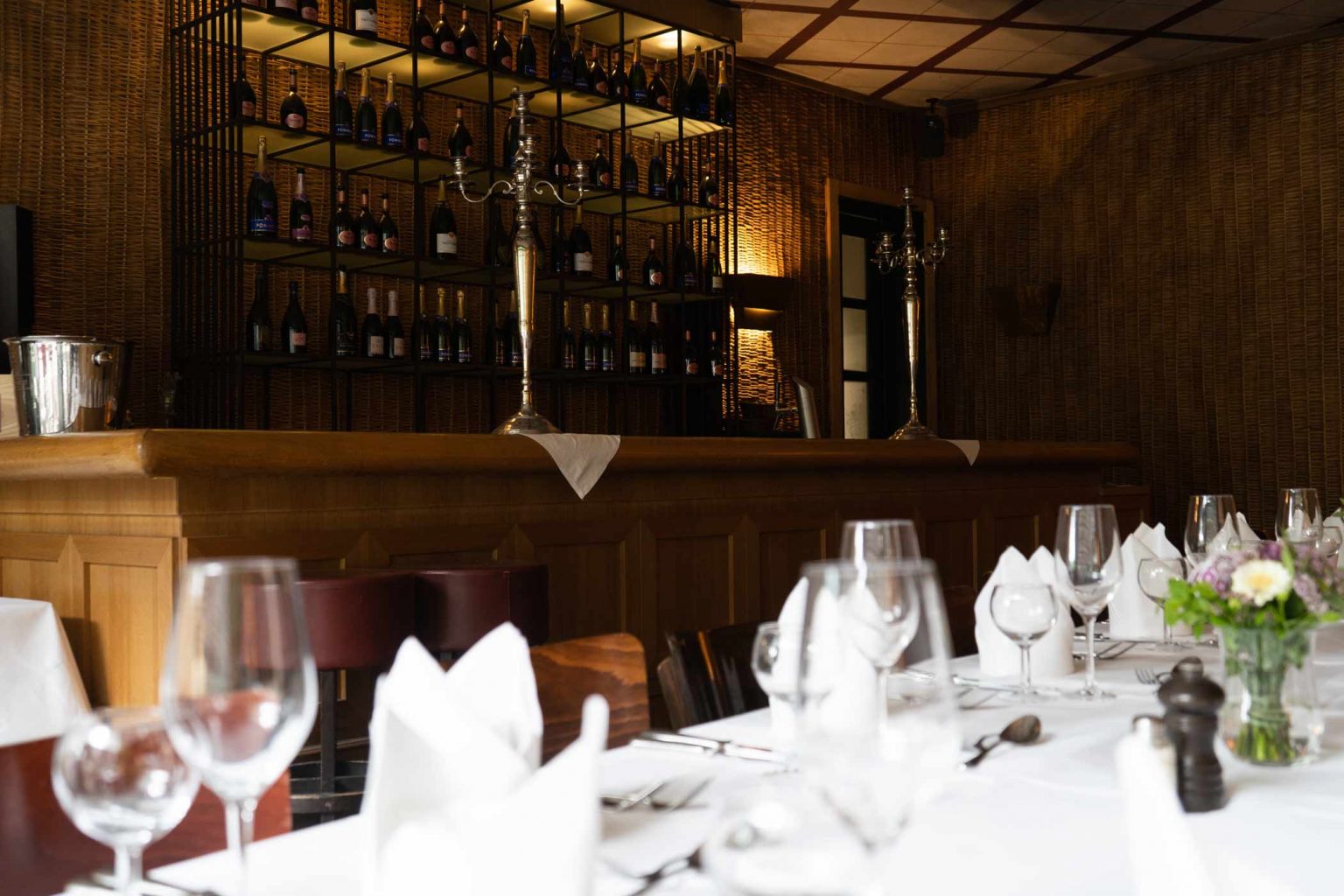 Festlich gedeckte Tische in der Bar & Lounge mit warmem Licht für Feiern und Events.
