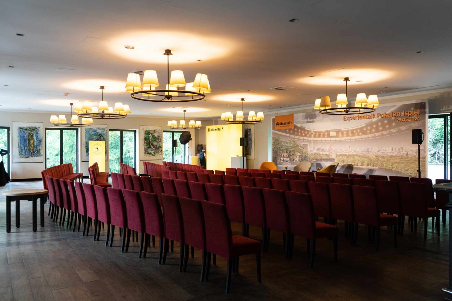 Festsaal mit roter Reihenbestuhlung und Bühne für Tagungen, Vorträge und Events.