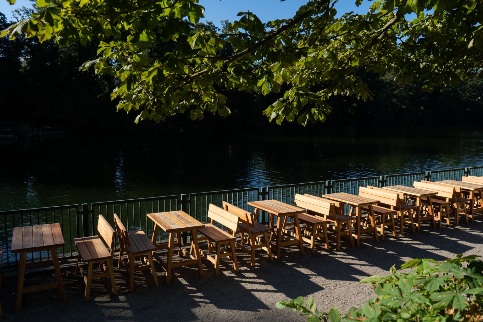 Biergarten-Terrasse mit Holztischen und Stühlen direkt am Seeufer.