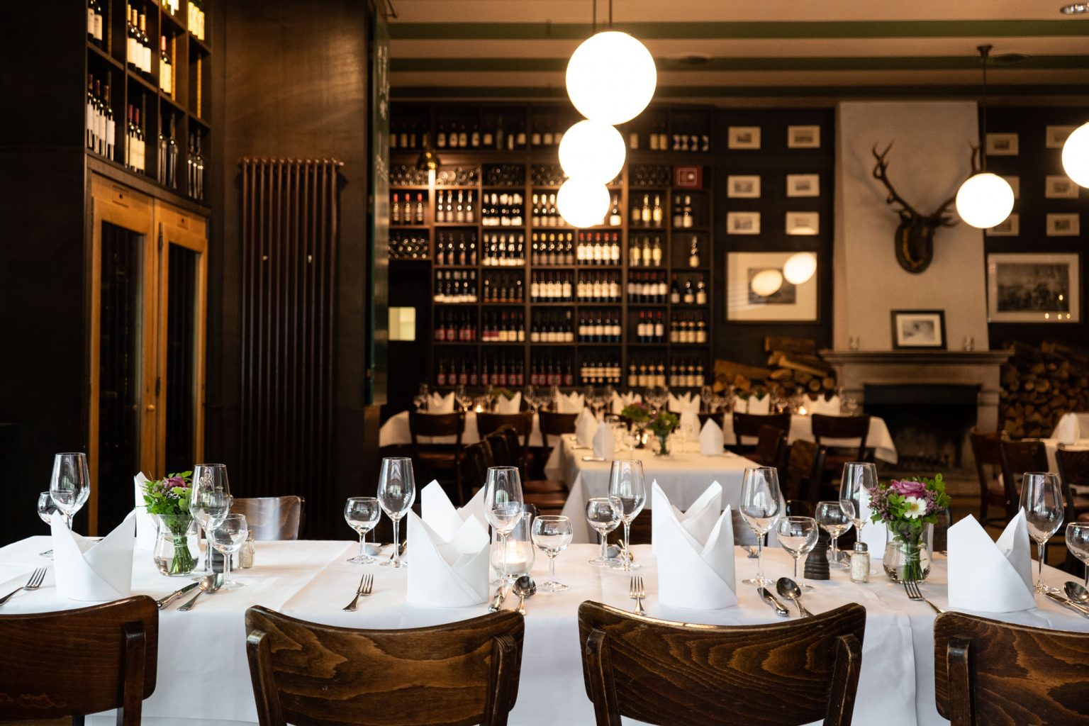 Stilvolle Weinhandlung mit Restaurant, festlich gedeckten Tischen und großen Weinregalen.