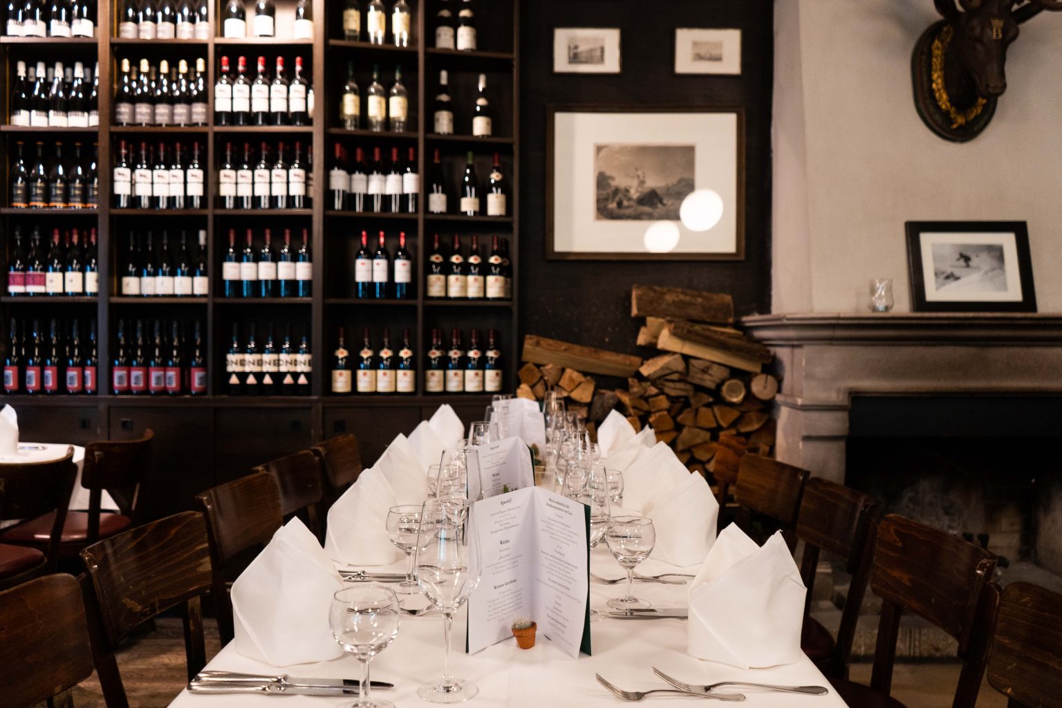 Festlich gedeckte Tafel in der Weinhandlung mit Weinregalen und weißen Servietten.