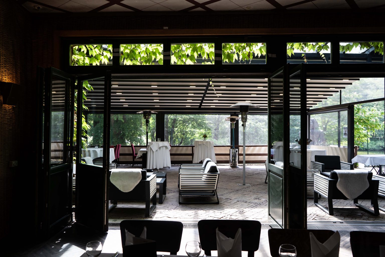 Heller Restaurant- und Loungebereich mit gedeckten Tischen und Blick ins Grüne.