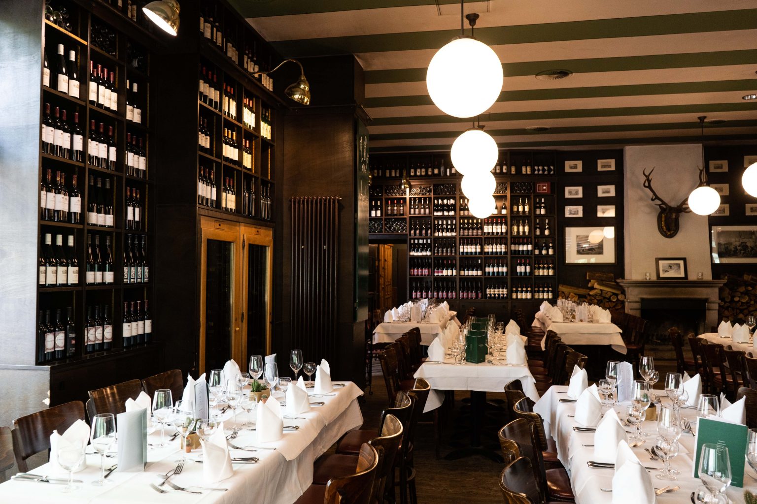 Restaurantbereich der Lutter & Wegner Weinhandlung mit gedeckten Tischen, Weinregalen und warmem Licht.