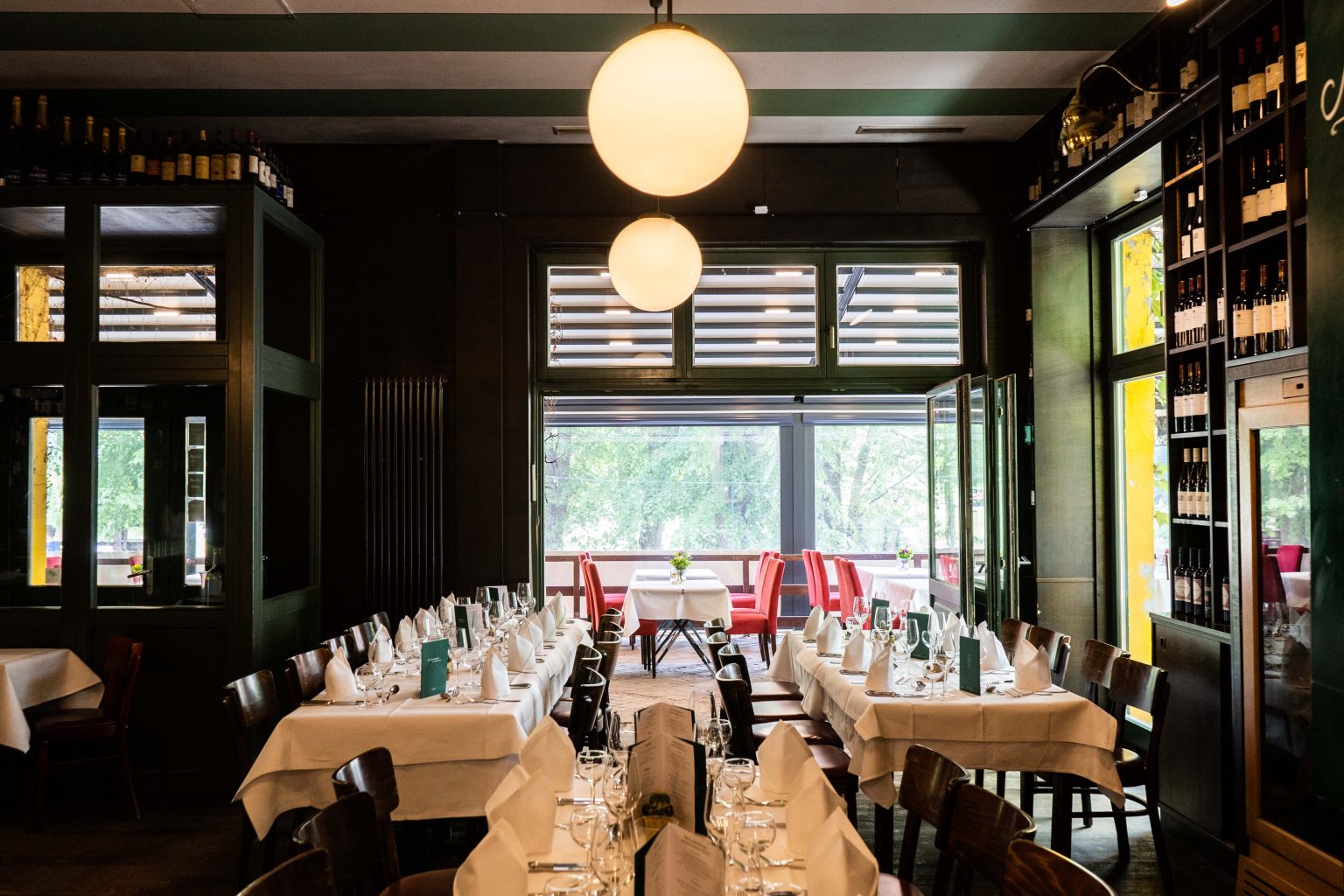 Restaurant in der Weinhandlung mit gedeckten Tischen, Barbereich und Blick nach draußen.