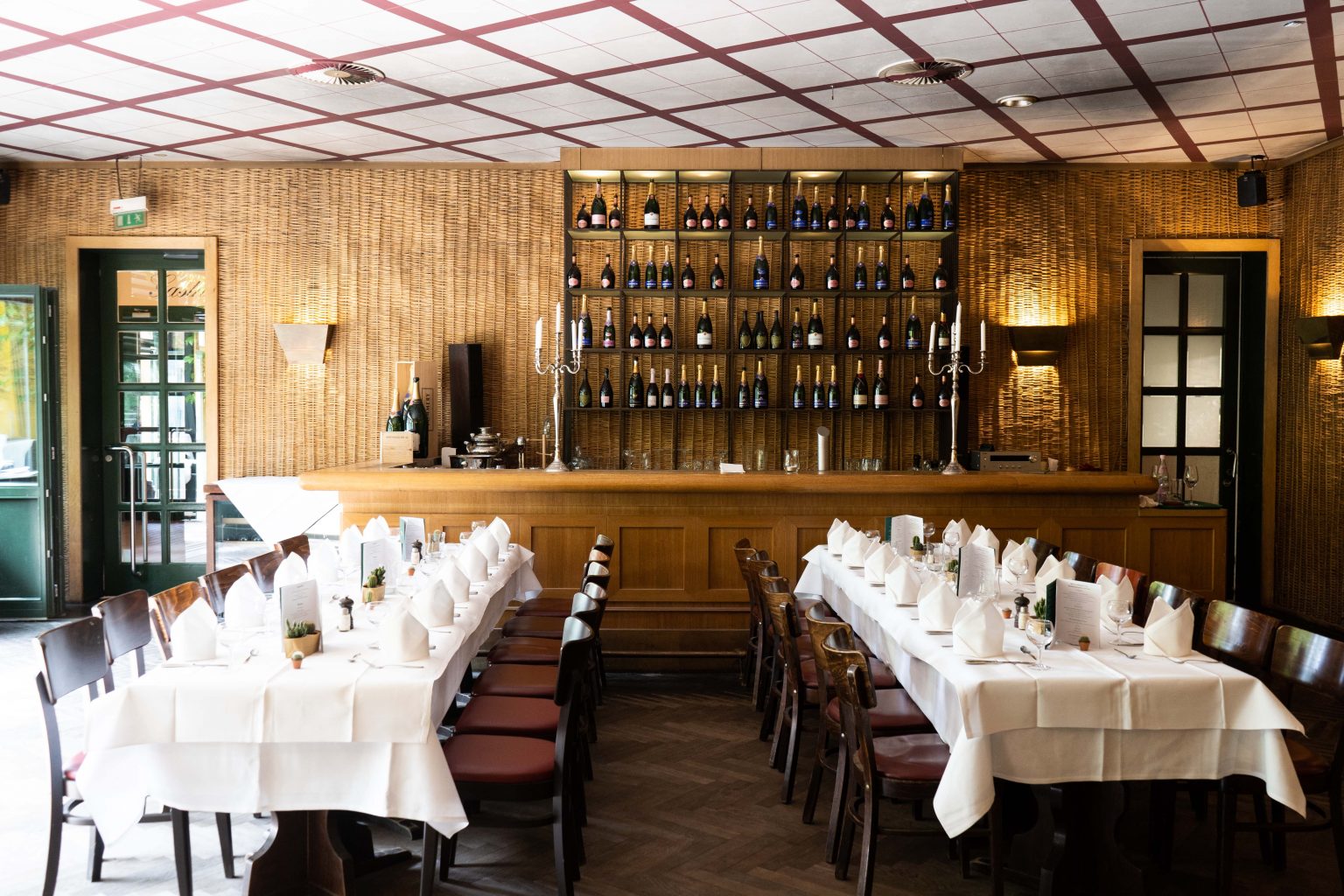 Bar & Lounge als stilvolle Eventlocation mit gedeckten Tischen, Holzbar und Weinregal.