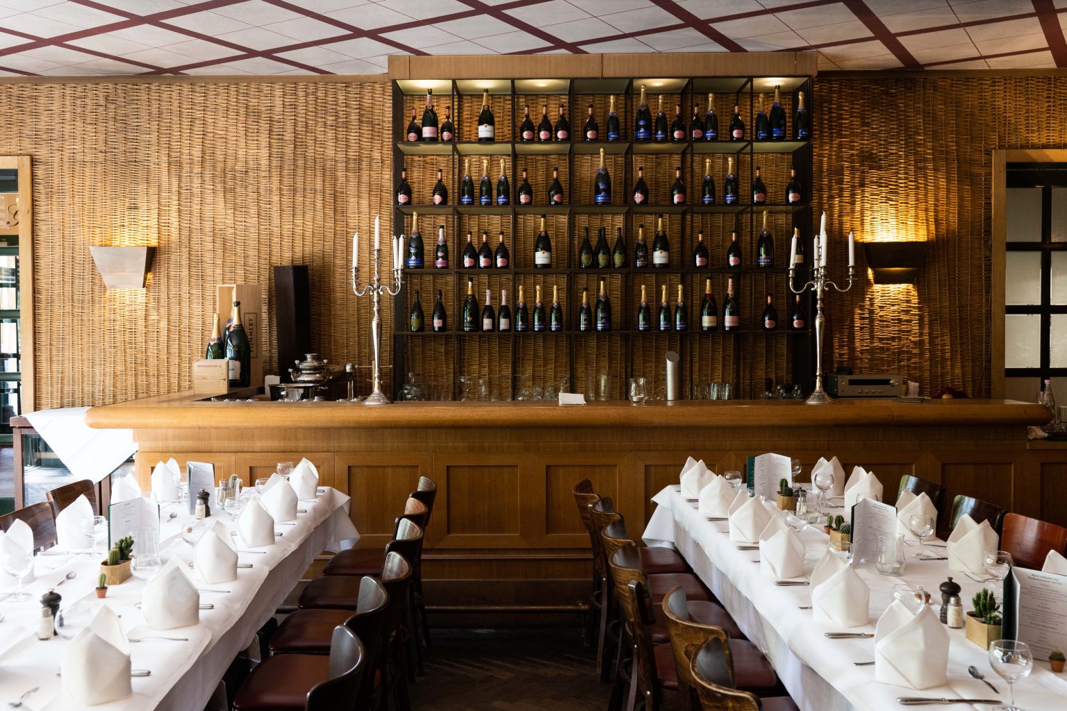 Bar & Lounge als stilvolle Eventlocation mit gedeckten Tischen, Holzbar und Weinregal.