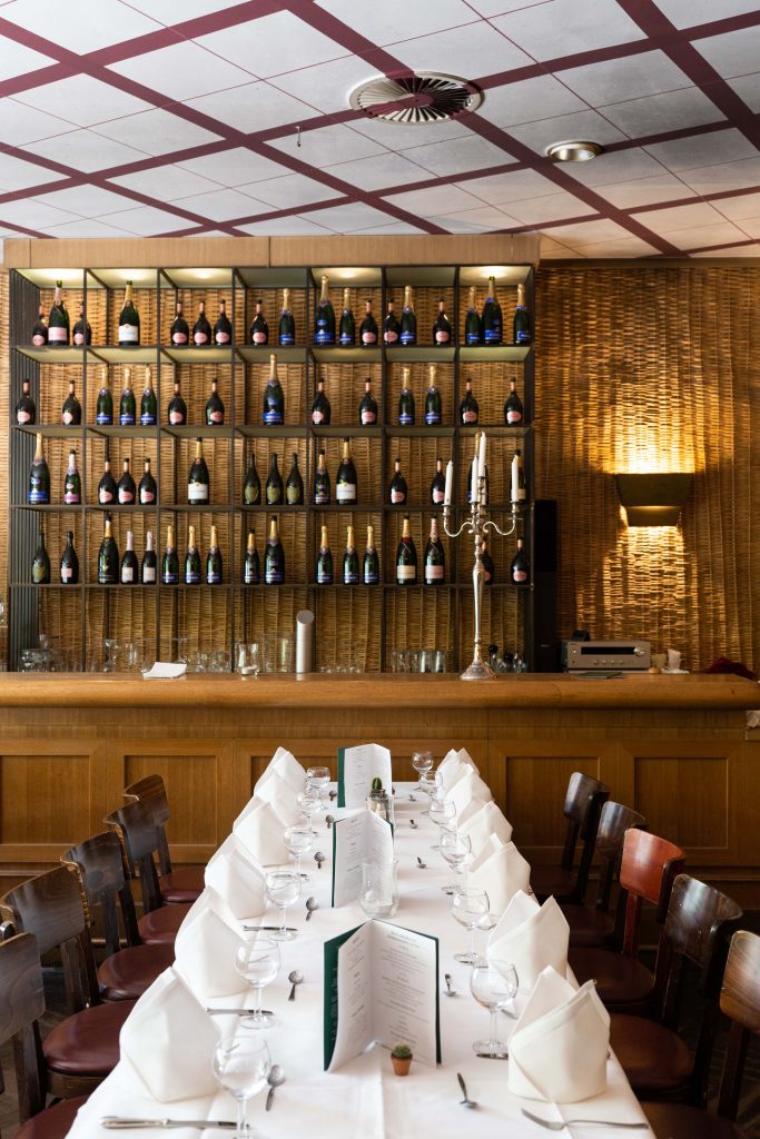 Elegante Bar & Lounge mit gedeckter Festtafel, warmem Holzambiente und umfangreicher Weinauswahl.