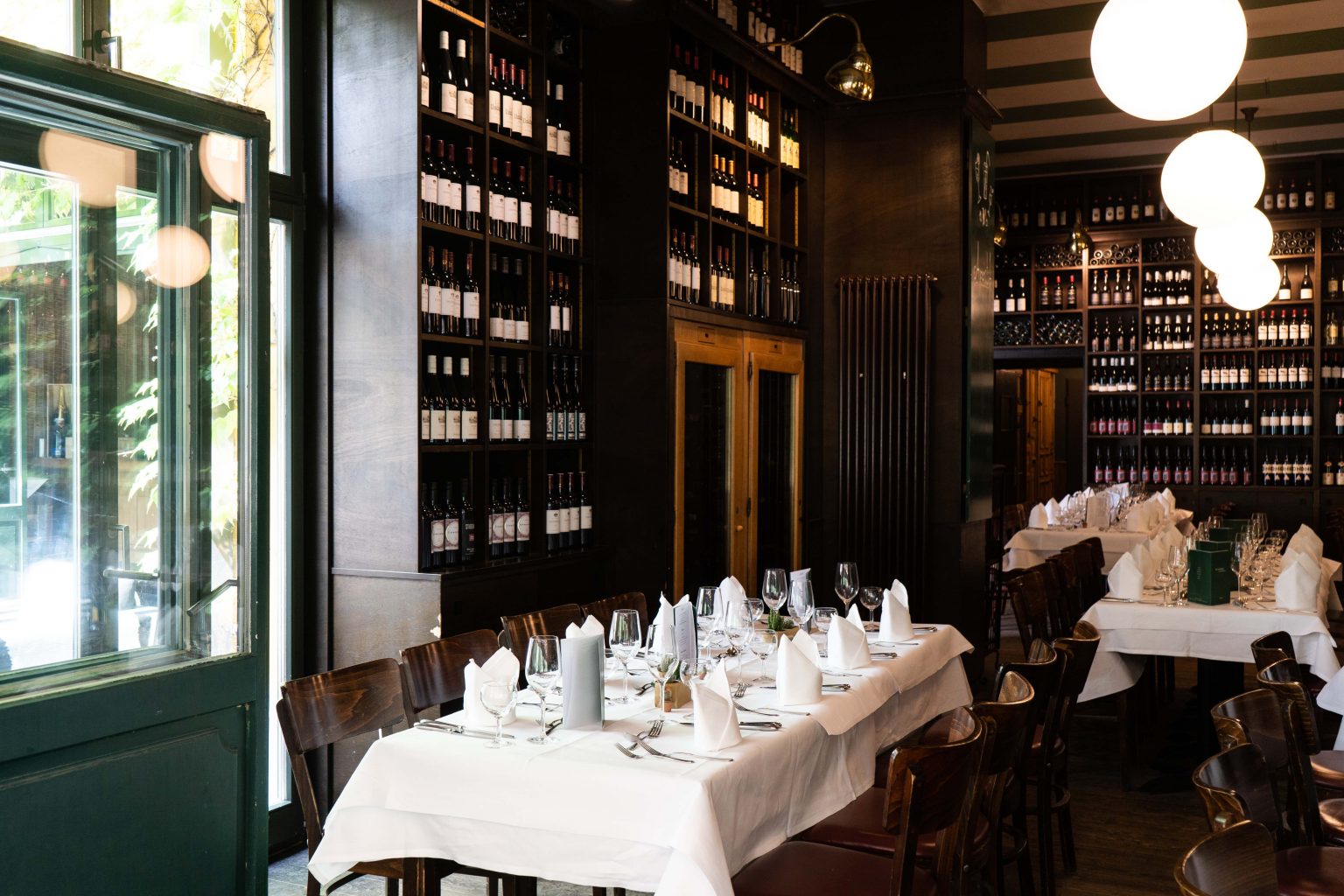 Gemütliches Restaurant mit gedeckten Tischen, Holzstühlen und Weinregalen für Feiern.