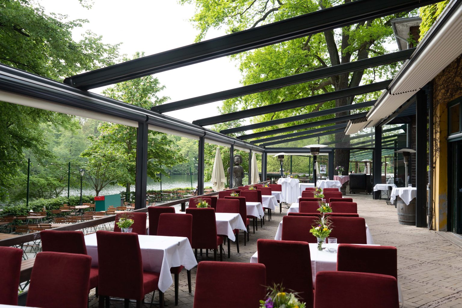 Überdachte Restaurant-Terrasse mit gedeckten Tischen und roten Stühlen für Veranstaltungen.