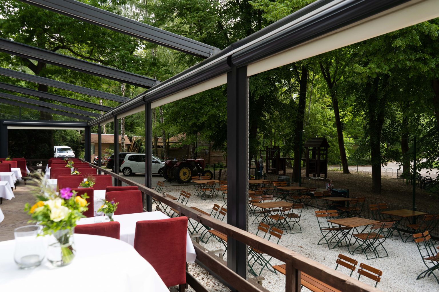 Stilvolle Außenterrasse mit weiß gedeckten Tischen, roten Stühlen und Pergola.