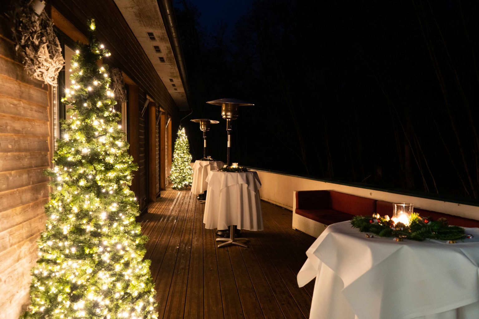 Außenansicht des festlich beleuchteten Festsaals mit Weihnachtsbaum am Abend.
