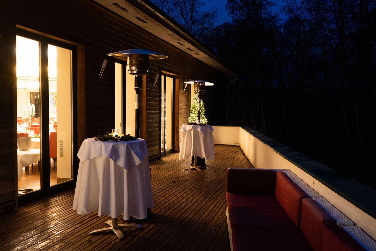 Festlich beleuchtete Terrasse am Abend mit gedecktem Stehtisch und Blick ins Grüne.